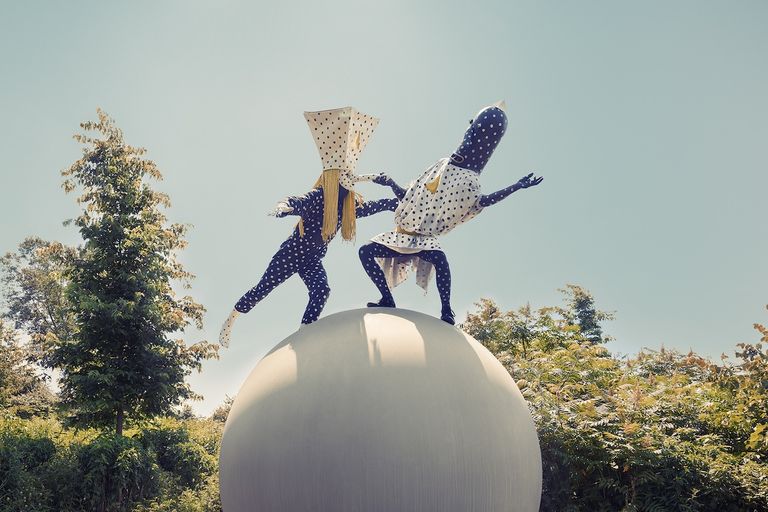 Musical group Angine de Poitrine performing in polka-dot costumes atop a giant sphere.